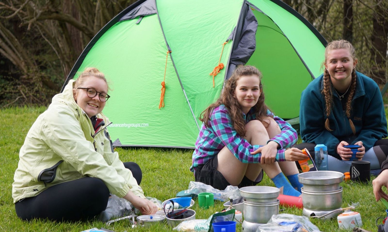 Group of girls sitting by their stoves cooking dunner on a DofE expedition.