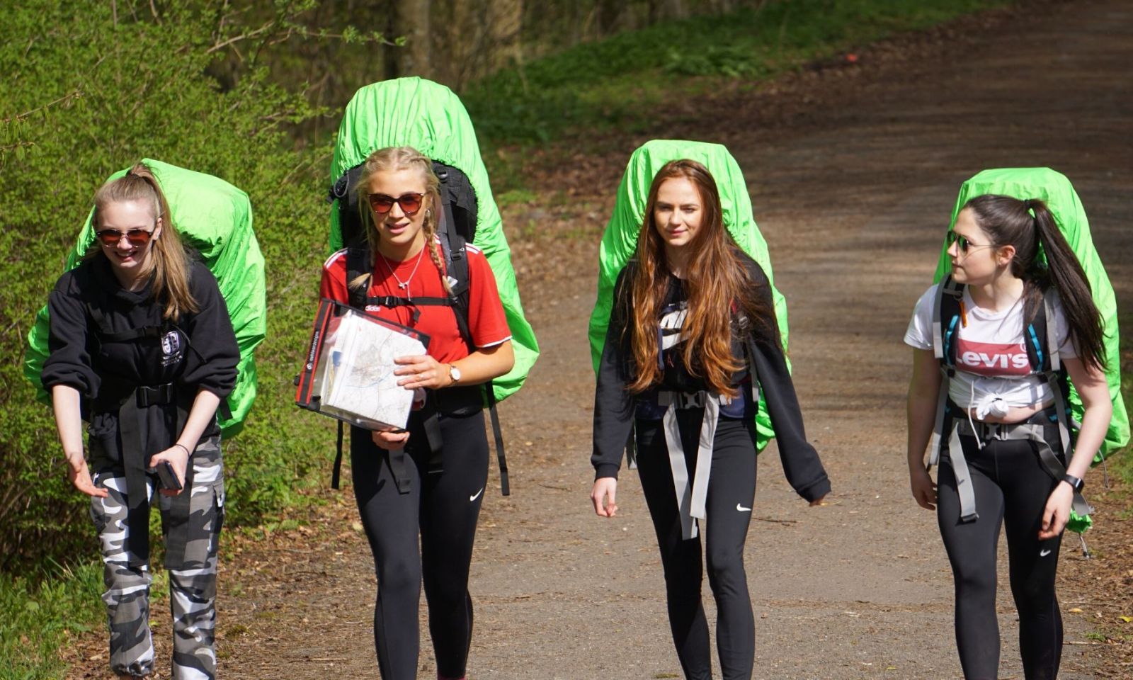 Four young people on their DofE expedition, walking with their rucksacks and map