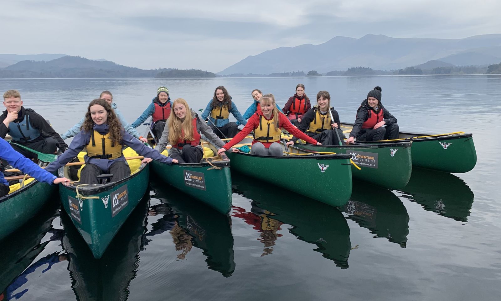 4 people in canoes smiling and having fun on the lake.