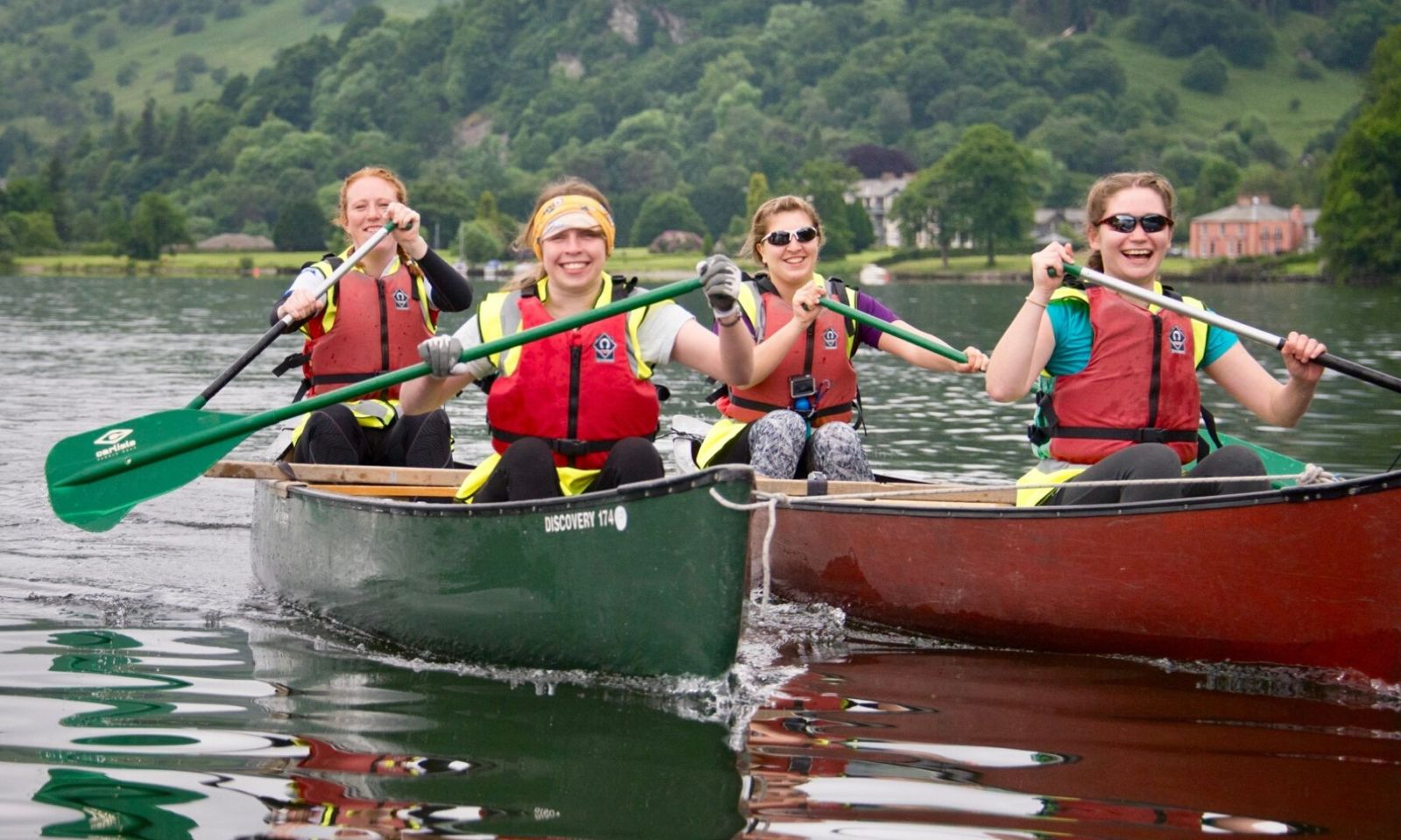 4 people in canoes smiling and having fun on the lake.