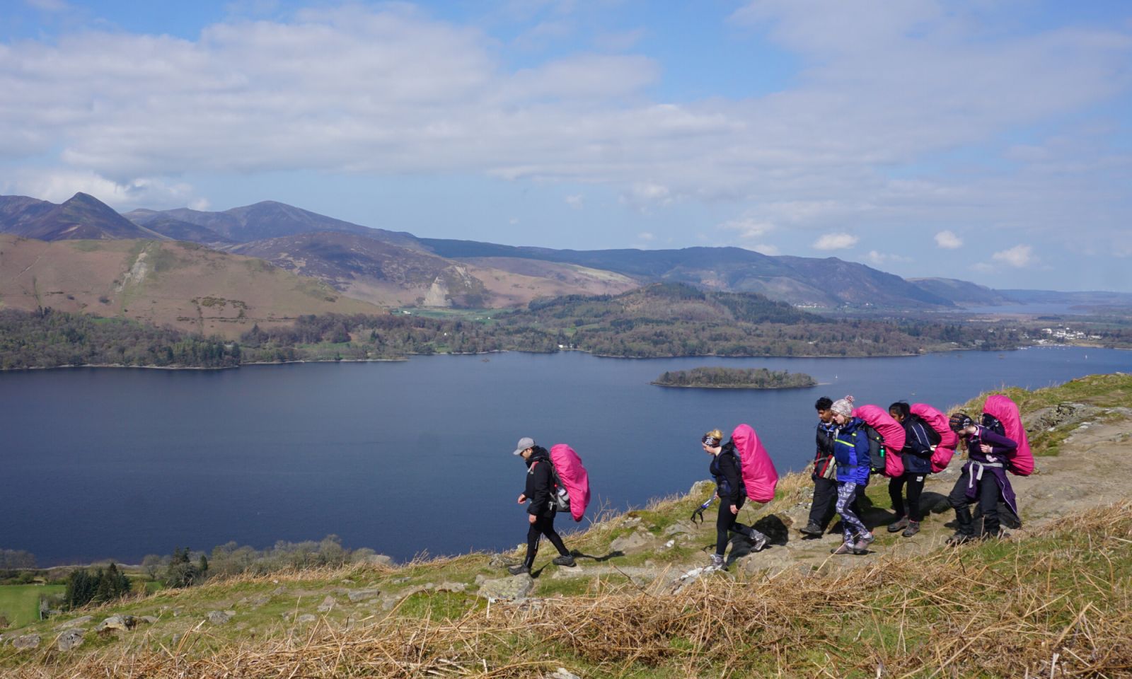 Group of Bronze DofE students walking in the hills with a lake and mountains in view
