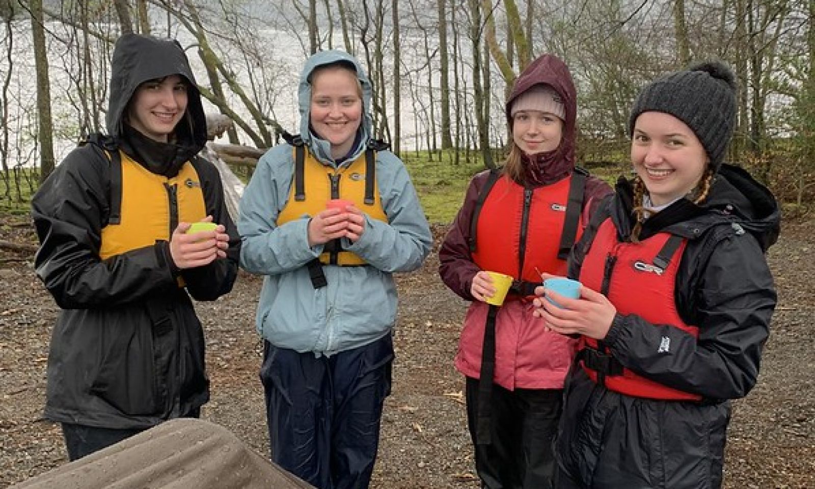 4 schools with a warm drink in the woods after a paddling with their life vests on