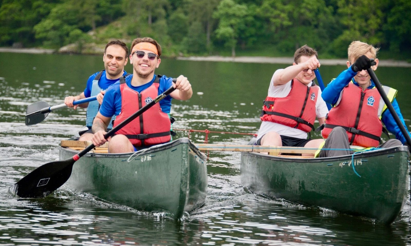 4 people in canoes smiling and having fun on the lake.
