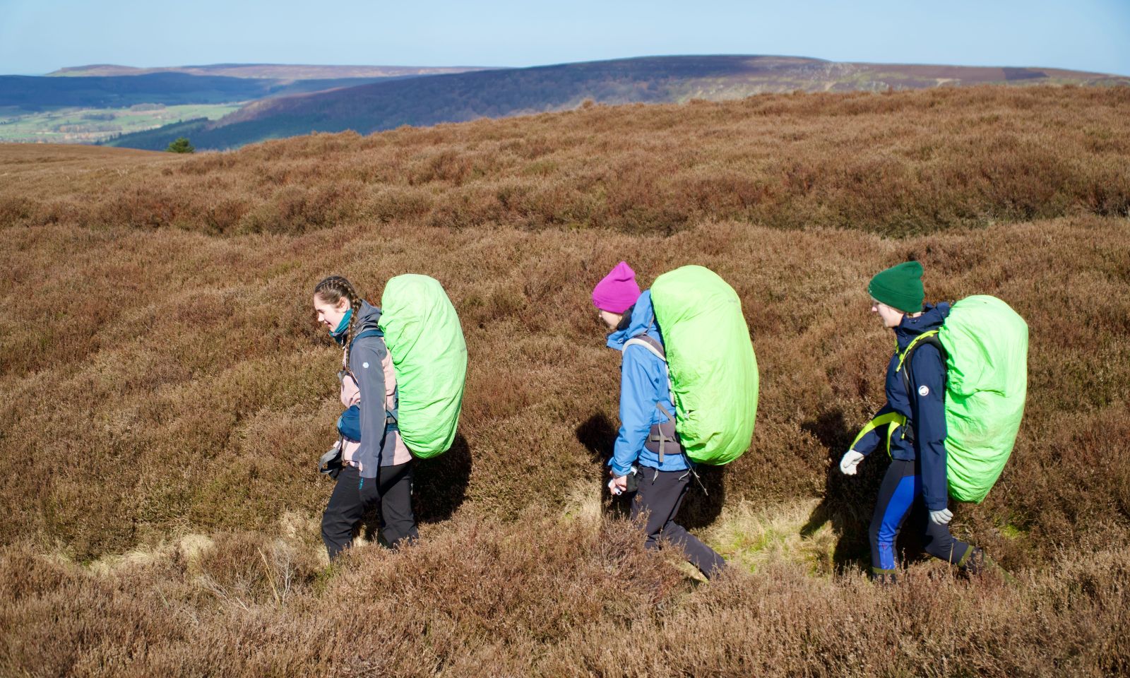 Duke of Edinburgh students with fully packed rucksacks making their way across heathland