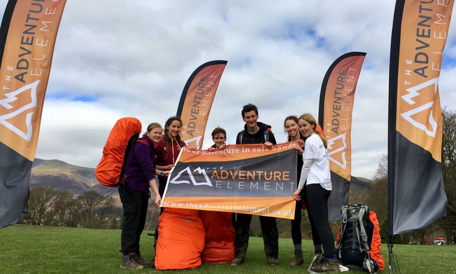 Team smiling and looking happy holding company flag after completing their DofE expedition.