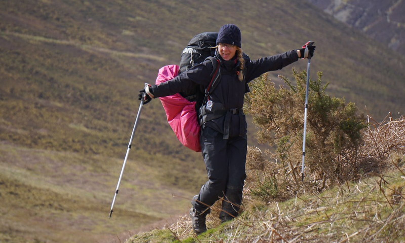 DofE participant in the hills smiling with her walking poles