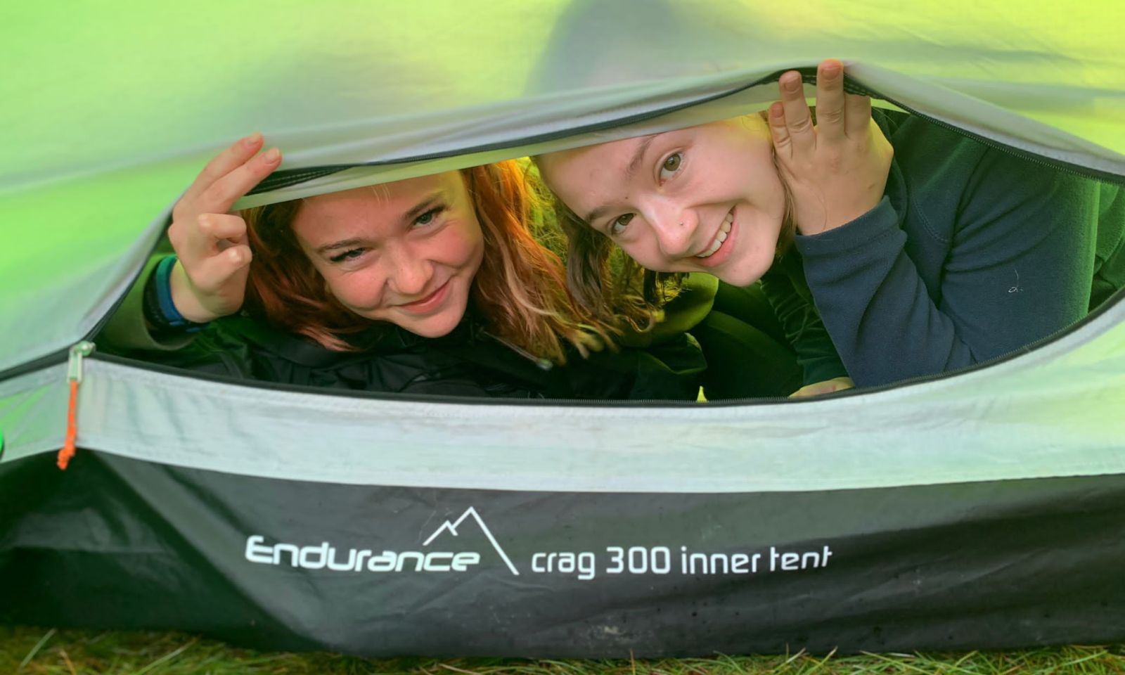 Two young girls looking out of their tent