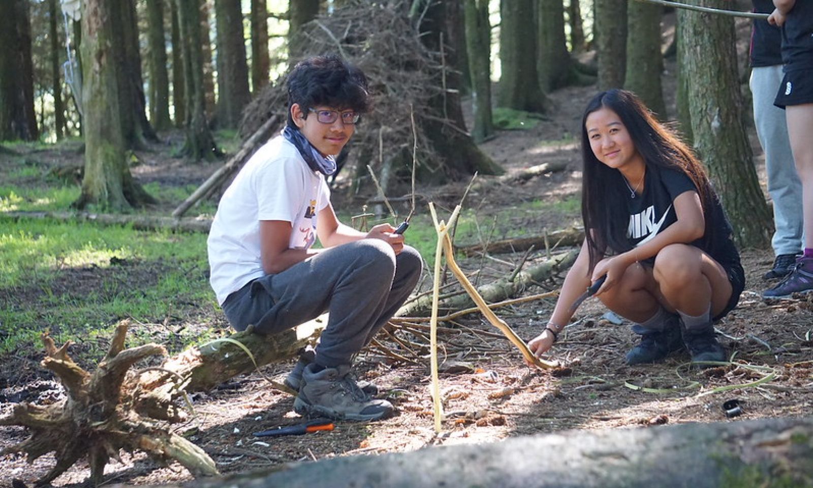Two young people in a forest making a fire using twigs