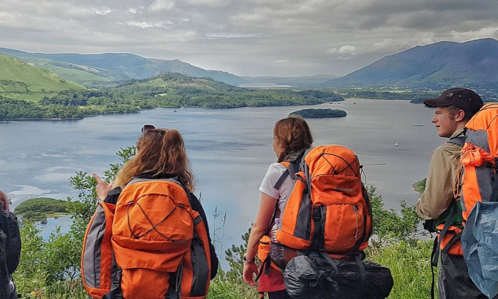 Group of 4 DofE Students with their full rucksacks looking out over the mountains and lakes of the Lake District